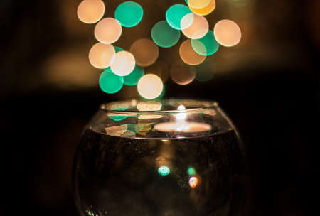 candle in a vase with water against garland sparksの写真素材