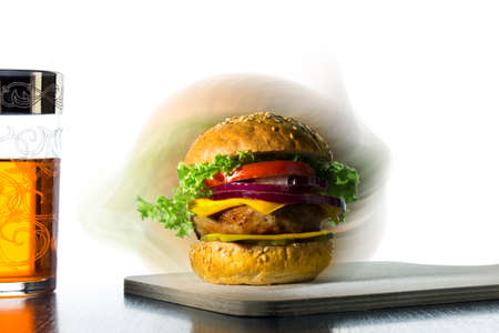 hamburger with cheese, onions, cucumbers and a glass with a drinkの写真素材