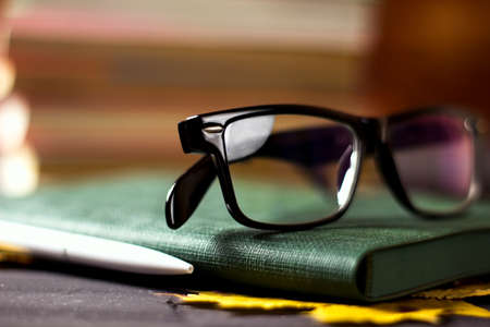 Notebook with glasses, a cup and books, maple leaves on a stone tableの写真素材