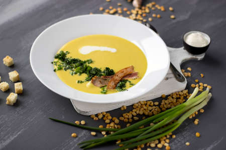 Pea soup with pieces of bacon, parsley and onion in a bowl on a gray background. Pea cream soup.の写真素材