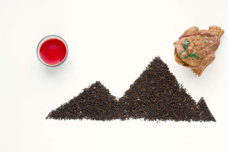 Oolong tea fresh red tea in a cup and black tea scattered in the shape of mountainsの写真素材