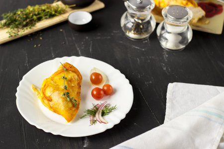 Baked chicken breast with onions and tomatoes on a white plate. Healthy food.