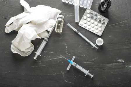 Medical ampoules with vaccine and syringe on gray background, top view. Medical ampoules with pure...