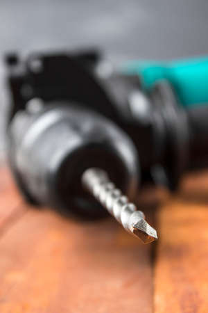 Industrial hammer drill. Perforator with a drill on a wooden background.の写真素材