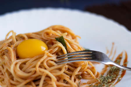 Delicious pasta with egg yolk, on wooden table.の写真素材