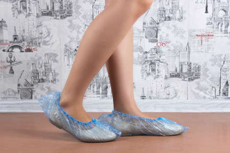 Woman puts on blue shoe covers, close upの写真素材