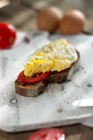 Poached egg on sourdough toast, with grilled tomatoes. A healthy, delicious breakfast or brunch.の写真素材