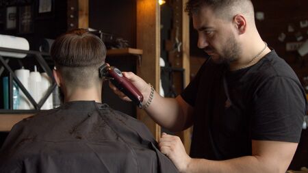 Young barber cutting hair of male clientの写真素材