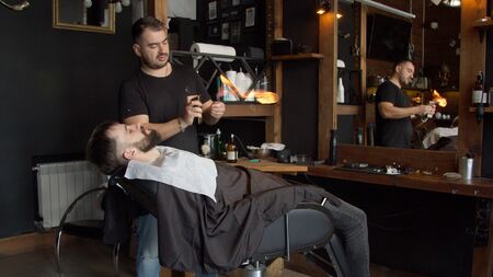 Young barber heating razor before shaving menの写真素材