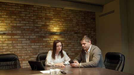 Colleagues looking at smartphone together with tabletの写真素材
