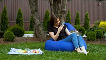 Young woman taking photo with kitten in gardenの写真素材