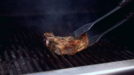 Man turning a piece of grilled meatの写真素材