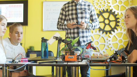 Unrecognizable students assembling car in robotics class