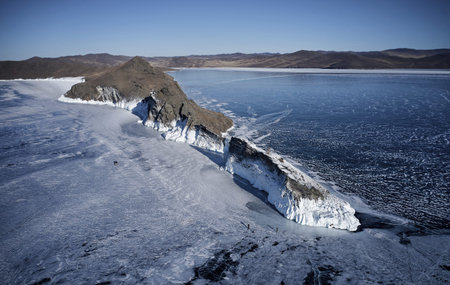 Frozen Lake Baikal, cape Horin-Irgi of Olkhon Island. Beautiful winter landscape with clear smooth...