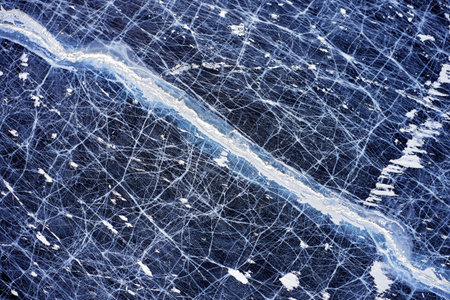 Frozen Lake Baikal, Aerial view. Beautiful winter landscape with clear smooth ice. Famous natural landmark Russia. Blue transparent ice with deep cracks, top view of a frozen lake.の写真素材