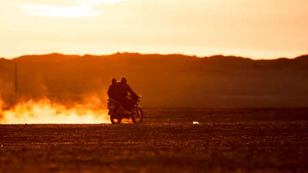 On a motorcycle in the Gobi desert. Dust from under the wheels. Wild Mongolian road.の写真素材