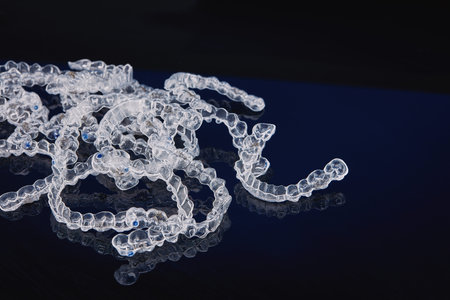Invisible orthodontics cosmetic brackets on black background, tooth aligners, plastic braces. Modern...
