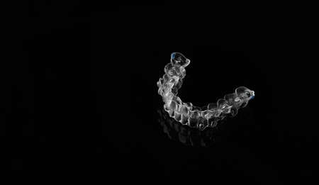 Invisible orthodontics cosmetic brackets on black background, tooth aligners, plastic braces. A way to have a beautiful smile and white teeth.の写真素材