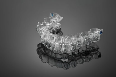 Invisible orthodontics cosmetic brackets on black background, tooth aligners, plastic braces. A way...