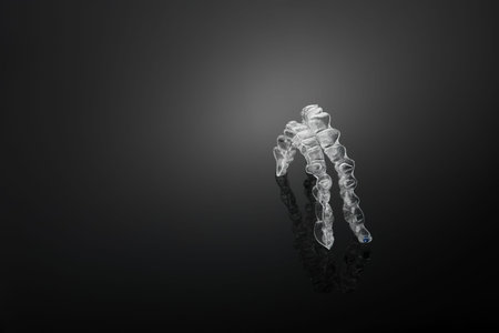 Invisible orthodontics cosmetic brackets on black background, tooth aligners, plastic braces. A way...