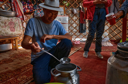 Life of the Mongolian Yurt. Interior of the nomad's house. The man pours some home brew, tasting of...