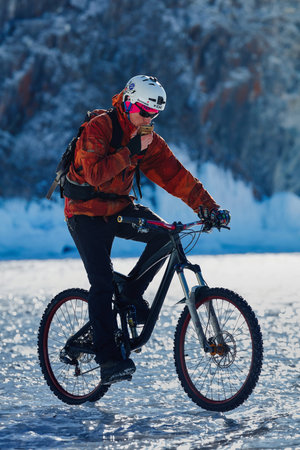 Bicycle tourist on the frozen lake. travel on sport bikes on the ice of a frozen lake near the beautiful icy rocks. 08/03/2019 BAIKAL LAKE, OLKHON ISLAND, IRKUTSK REGION, RUSSIA