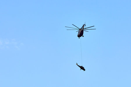 Transport helicopter Mi-26 T2B transports the fuselage of a combat helicopter on the external...