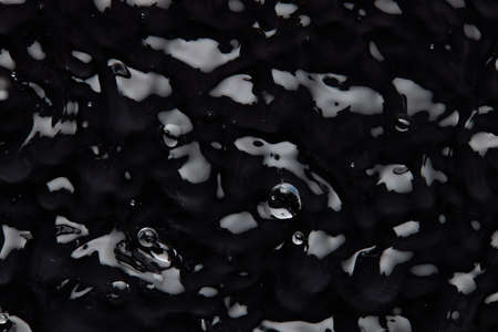 Splashes and drops on the surface of the liquid. Abstract Black Background Liquid Texture.の写真素材