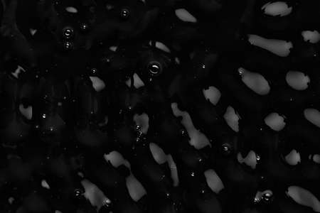 Splashes and drops on the surface of the liquid. Abstract Black Background Liquid Texture.の写真素材