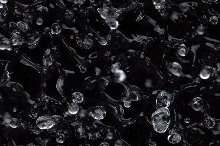 Splashes and drops on the surface of the liquid. Abstract Black Background Liquid Texture.の写真素材