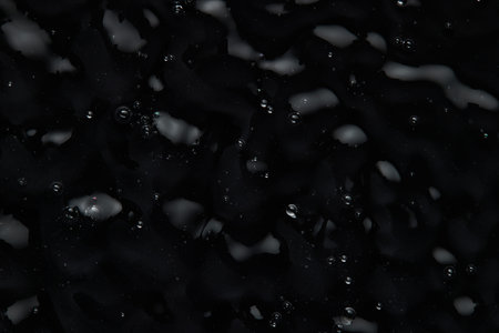 Splashes and drops on the surface of the liquid. Abstract Black Background Liquid Texture.