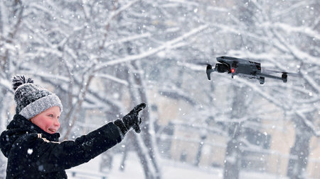 Teenager boy dressed winter jacket and modern digital drone DJI Mavic, flying in snow conditions. DJI Mavic 3 most portable drones with Hasselblad camera. 25.01.2022 Rostov-on-Don, Russiaのeditorial素材