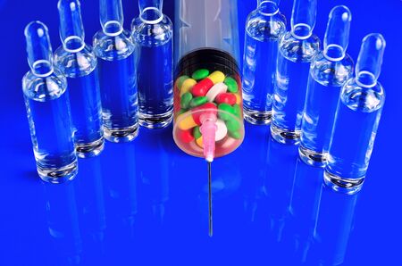 Syringe for subcutaneous injections with glass ampoules and multicolored tablets on an isolated background. Ampoule. Syringesの写真素材
