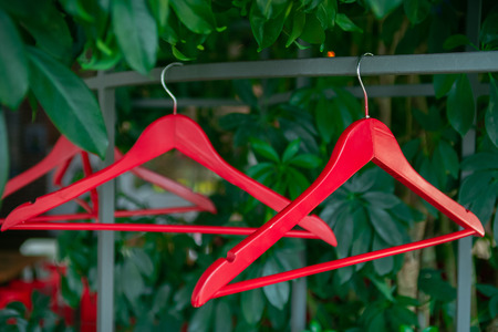 Hangers without clothes on the rack on the background of green leaves.の写真素材