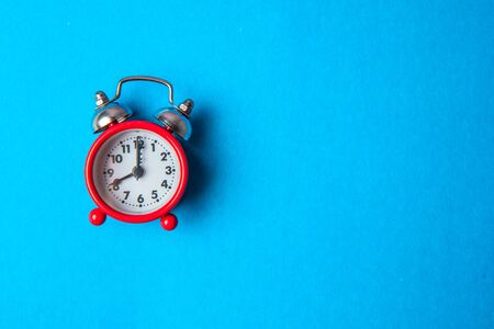 Back to school concept. Old red alarm clock on a blue background. Copy space.の写真素材