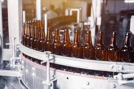 Glass beer bottles of brown color on the conveyor line of beer bottling close upの写真素材