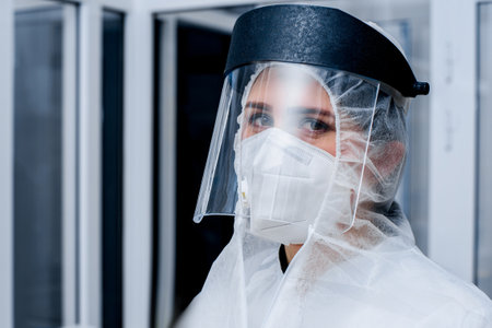 Portrait of a female medic in a protective suit and a plastic mask on her face in a laboratory.の写真素材