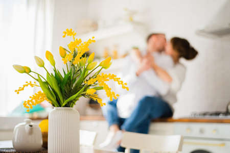 Bouquet of yellow tulips in a vase against the background of a kissing young coupleの写真素材