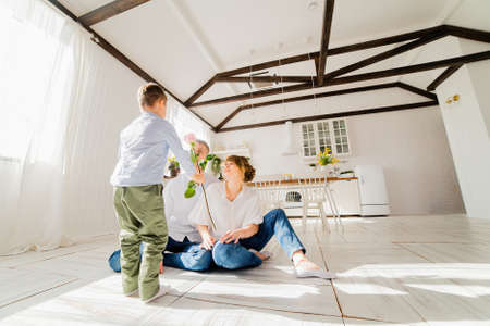 Little boy gives a rose to young parentsの写真素材