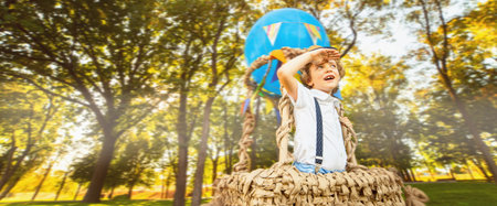 A little curly-haired boy in a hot air balloon looks into the distance. copy space banner.