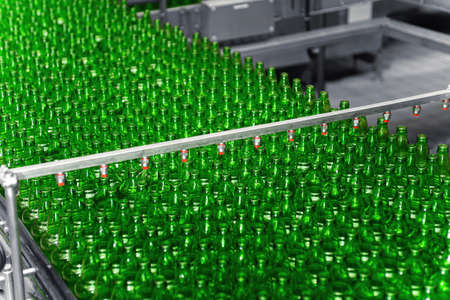 Automated conveyor line in a brewery. Rows of green glass bottles on a conveyor belt. Industrial breweryの写真素材