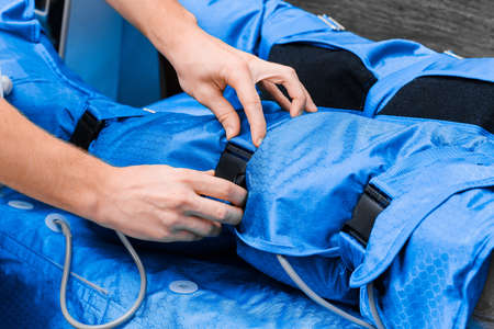 Close-up of doctor's hands on pressotherapy and lymphatic drainage massage suit.の写真素材