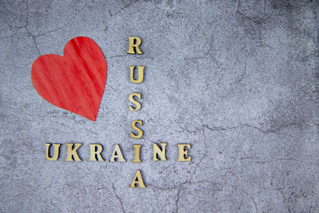 top view of the inscription with wooden letters Russia and Ukraine on a gray background and a red heart. The concept of peace, friendship, love and kindnessの写真素材