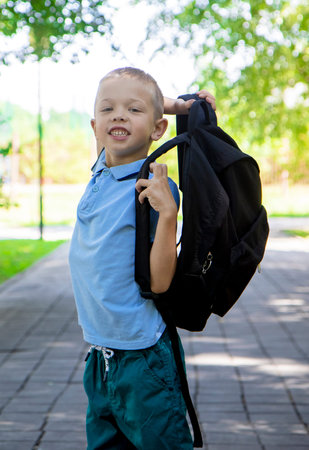 back to school. Portrait of an elementary school student on the way to study. A child boy with a backpack goes to elementary school, on the street.の写真素材