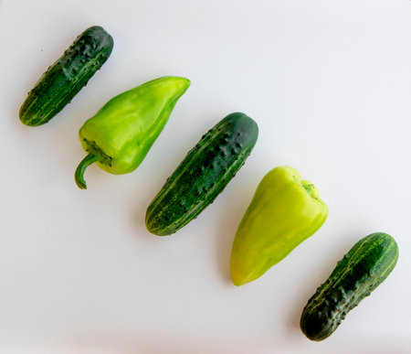 Ripe fresh green cucumber and bell pepper, laid out in a row, is highlighted on a white background. A young summer harvest, vitamins and proper healthy nutrition.hの写真素材