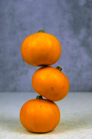 Bright and orange three pumpkins stacked on top of each other. The concept of the Halloween holiday, the autumn harvest.の写真素材