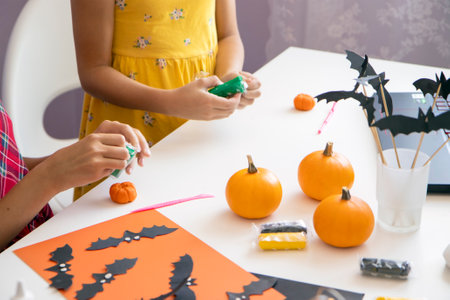 selective focus on the hands of two children, they are sitting at a table and sculpting plasticine decorations for Halloween. The concept of decorating the holiday with children's craftsの写真素材