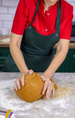 View of a pastry chefs woman in red and green work clothes. She kneads the dough for making...