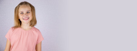 Banner portrait of a cute baby girl on a light background, a little blonde girl looks at the camera. copy spaceの写真素材