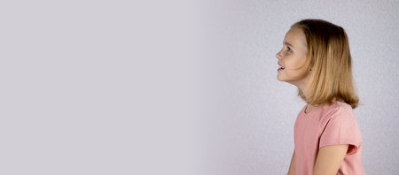 Banner portrait of a fair-haired baby girl on a white background, a little girl looks away with copyspace.の写真素材